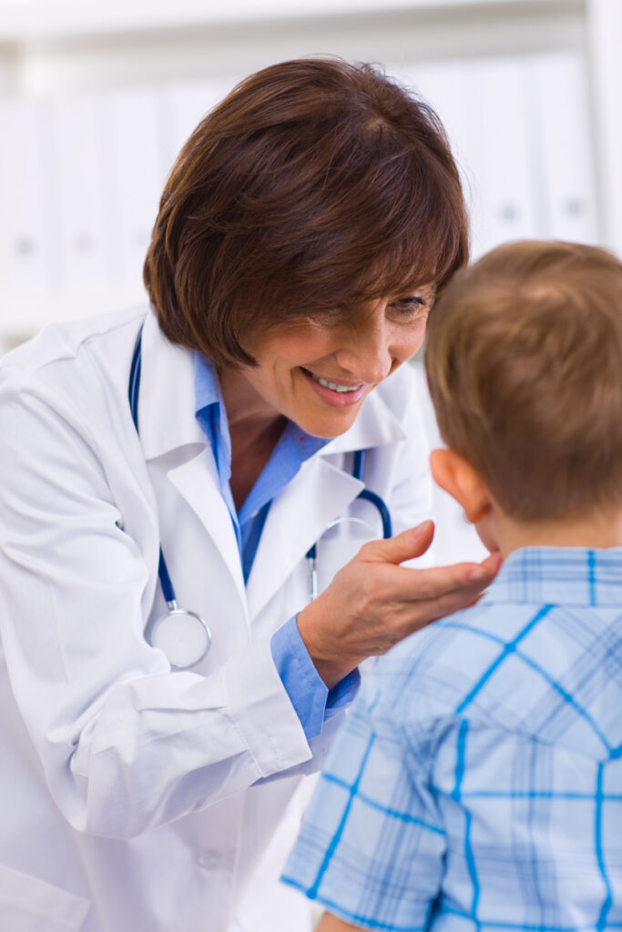 Mature female doctor examining little child boy.